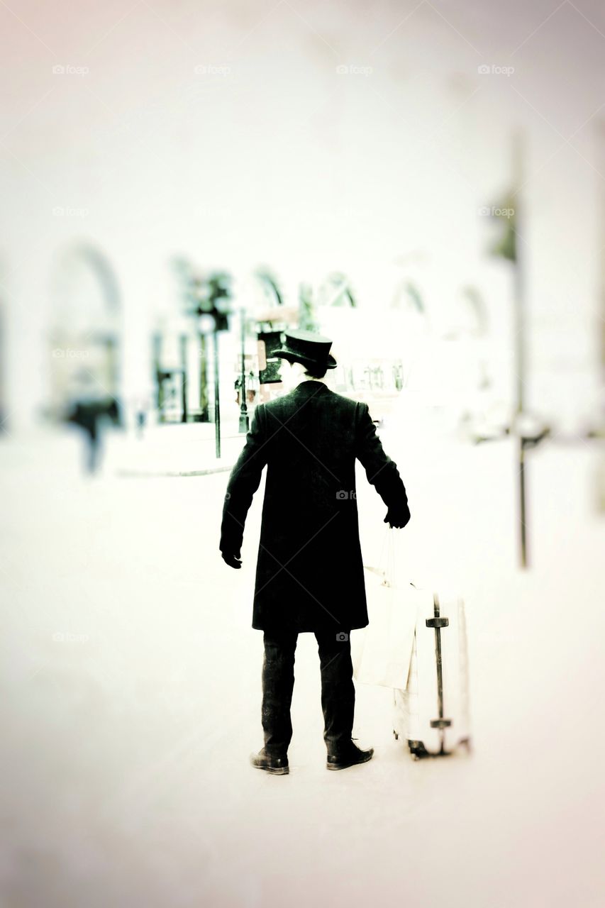 A butler on a busy London Street waiting with bags for a taxi cab.