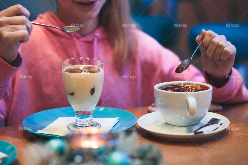 Girl eating a dessert and drinking a tea in coffee shop. Candid people, real moments, authentic situations