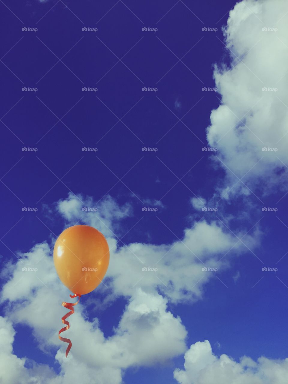 Low angle view of orange balloon on clouds