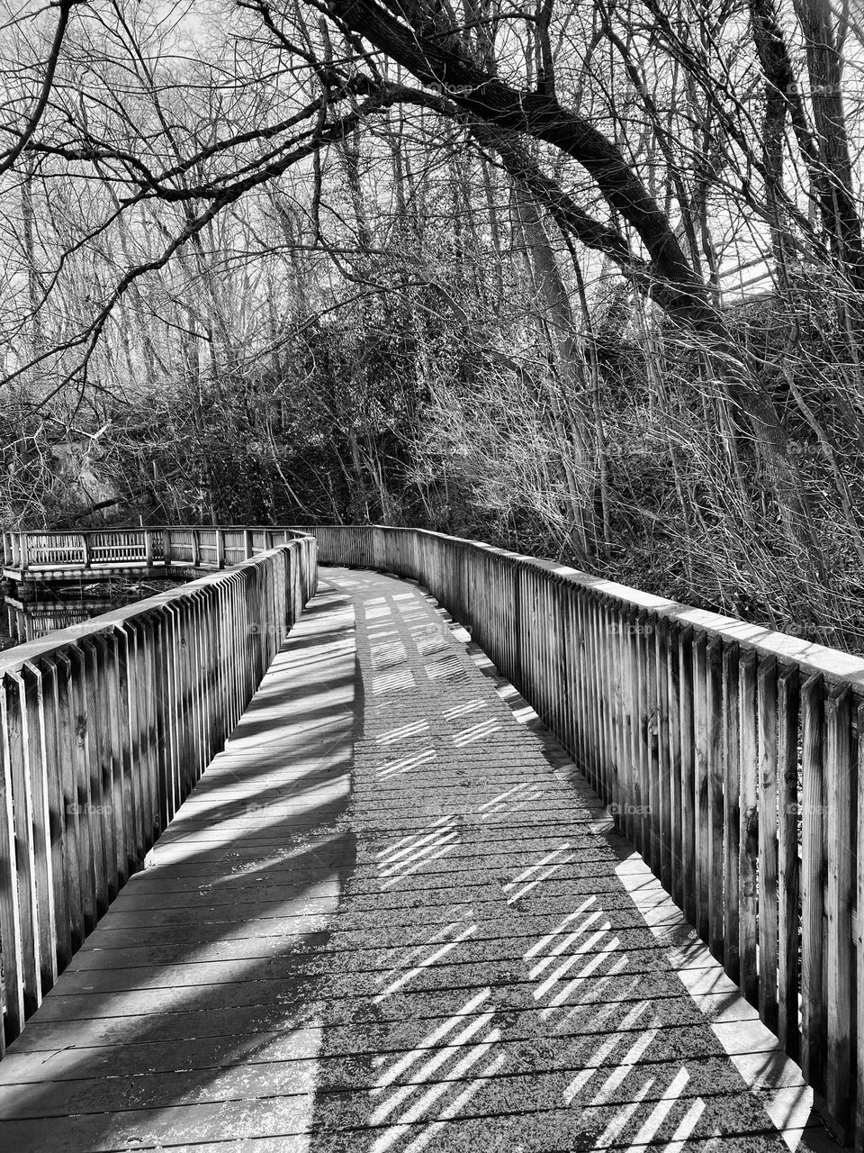 A boardwalk covered with some melting snow around the edge of a quarry lake at a local park