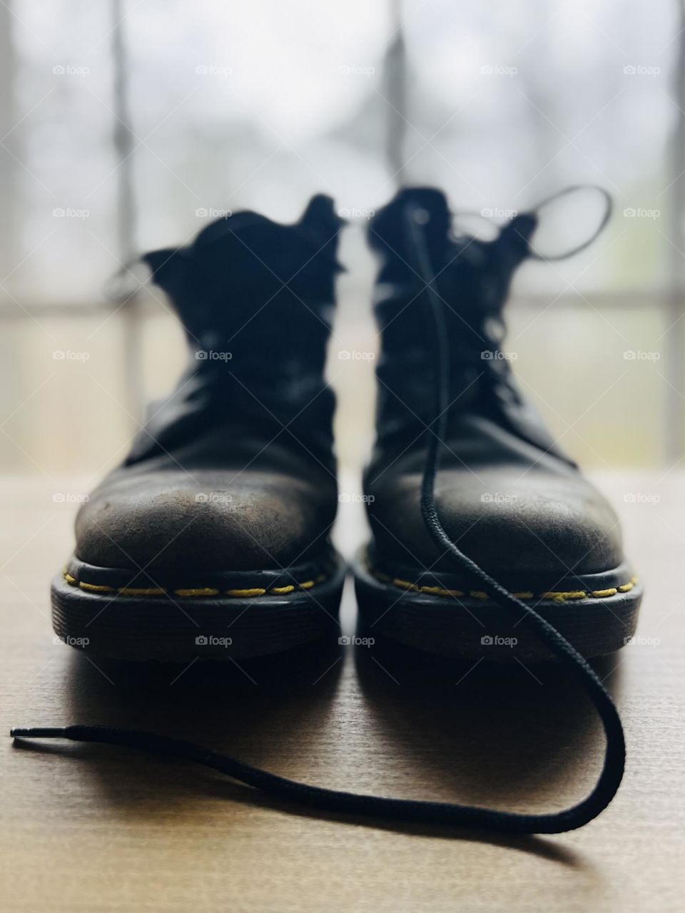 Closeup pair of worn classic Doc Marten boots backlit by window