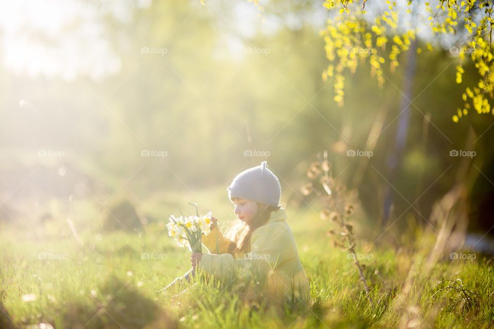 Little girl with narcissus bouquet in spring park