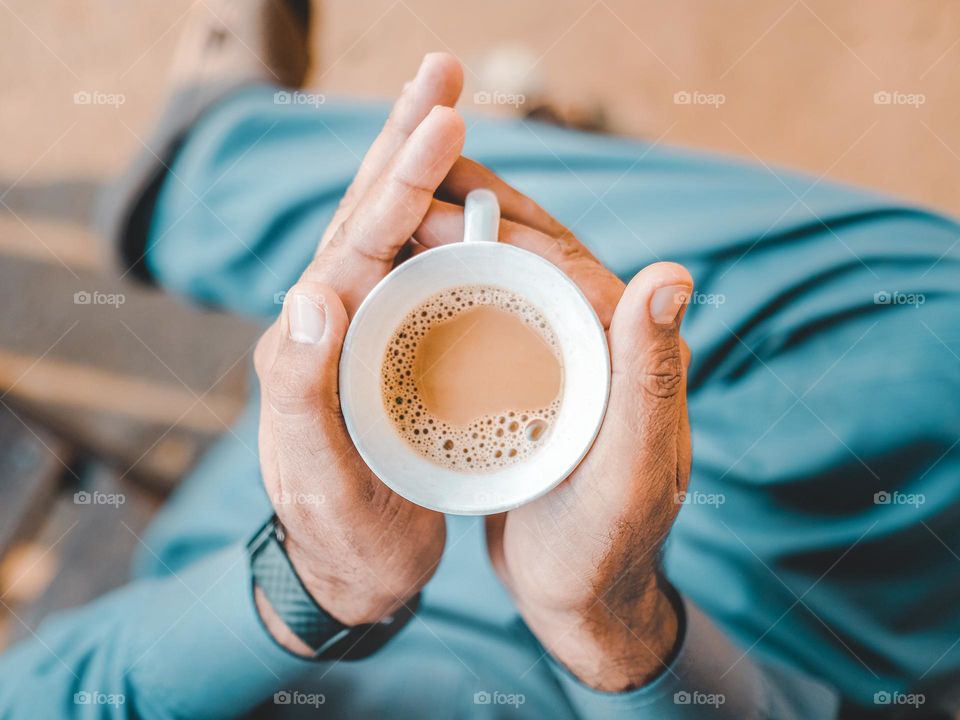 High angle view of a cropped hand holding a milk tea in a white cup