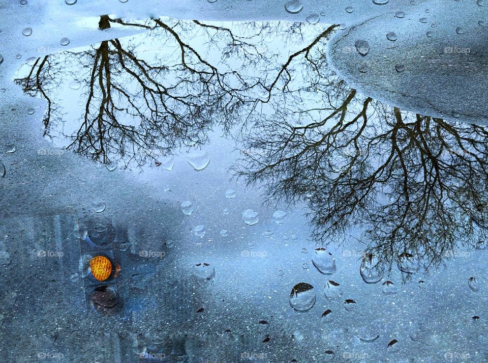 Orange traffic light reflected on wet pavement 