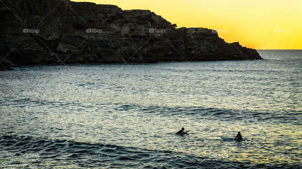 Sufers enjoy waves as the sun goes down 