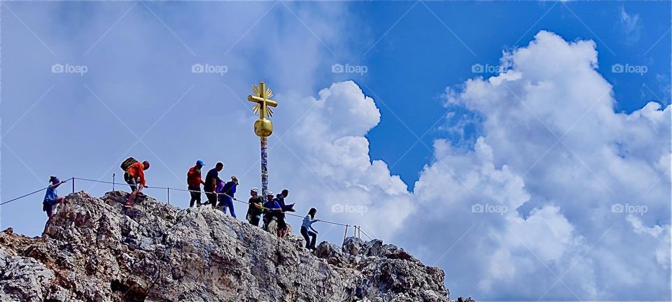 They all take in that glorious moment of reaching the highest peak of the “Zugspitze” standing beneath the summit cross with a golden globe and extending rays. At 2962 m it is the tallest mountain in the German “Alps”. 2024. Hypnotic Productions