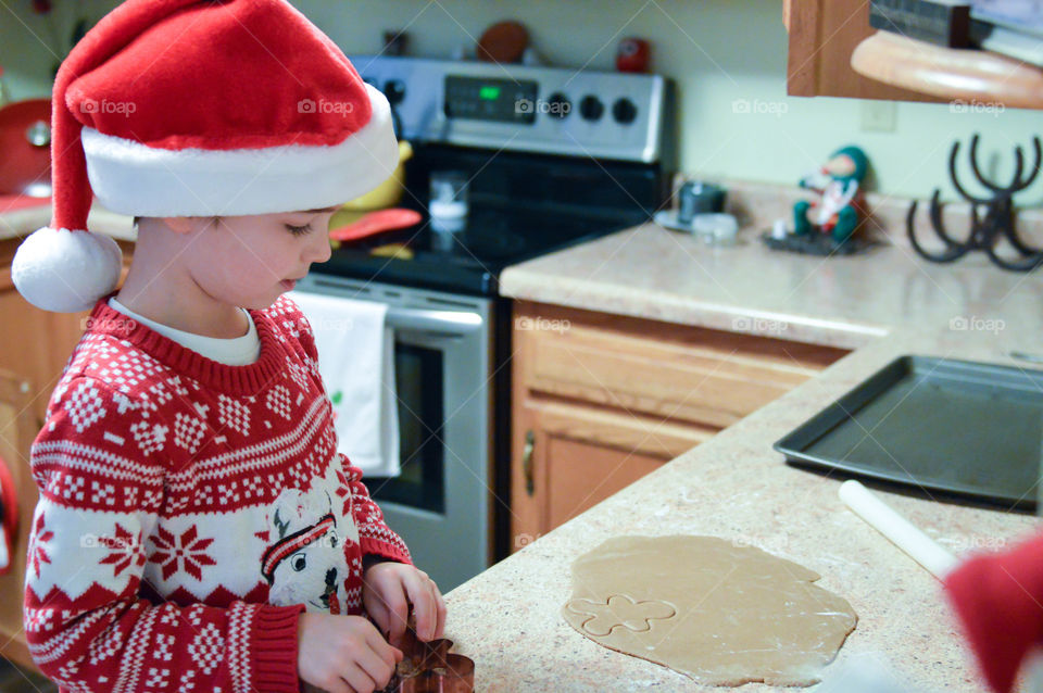Young boy wearing a Santa hat and baking Christmas cookies