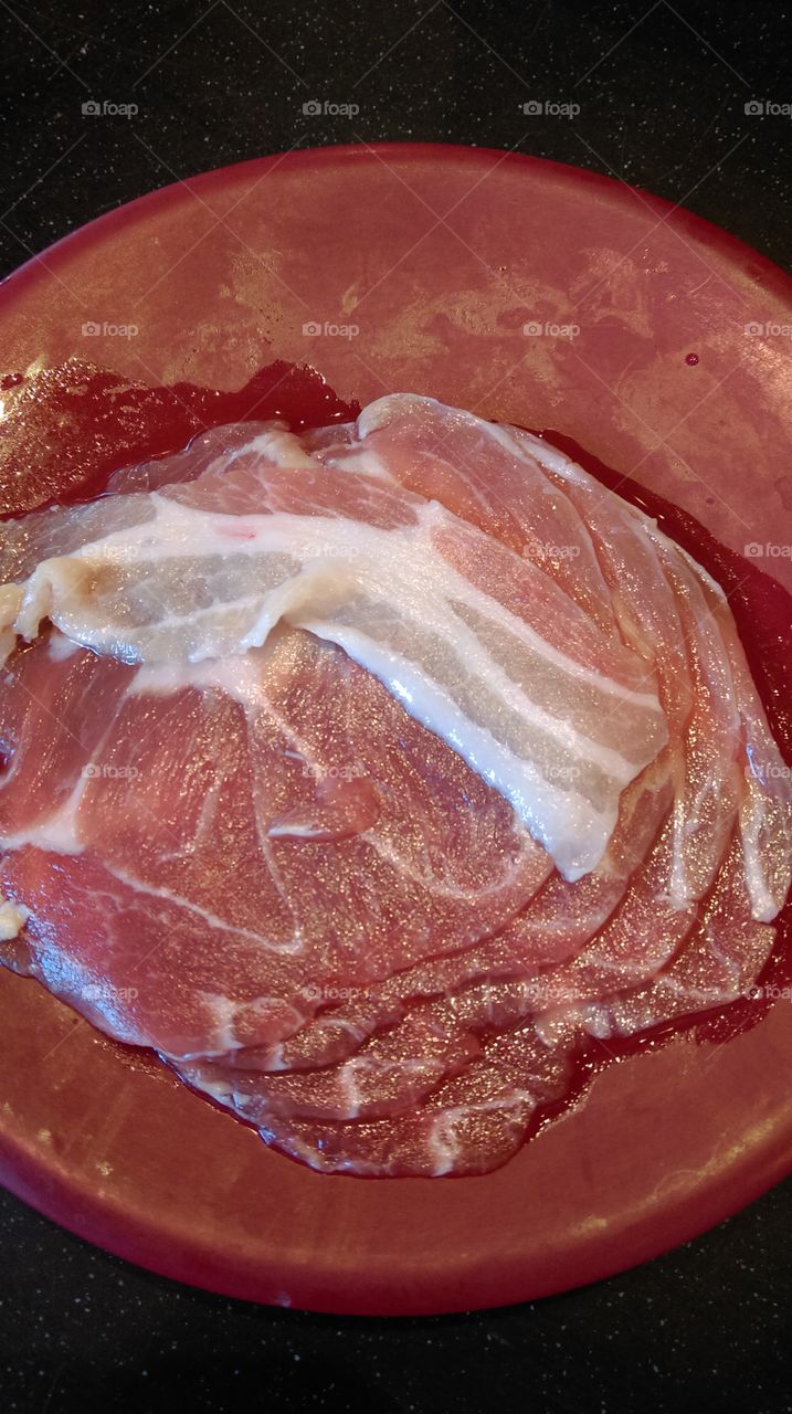 A red dish with raw sliced pork prepare for cooked.