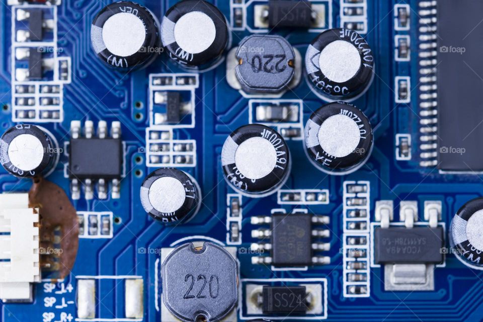 Blue printed Circuit Board with microchips and many electrical components.  capacitors close up