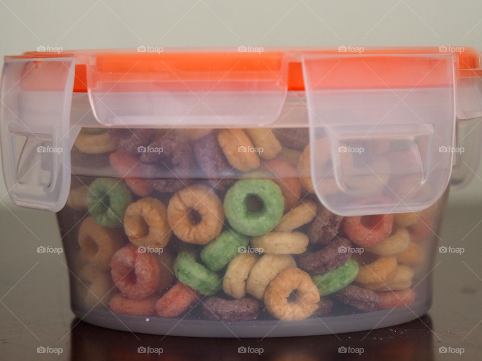 On-The-Go Toddler Snack. Colorful fruity o cereal in plastic see through container with snap on lid