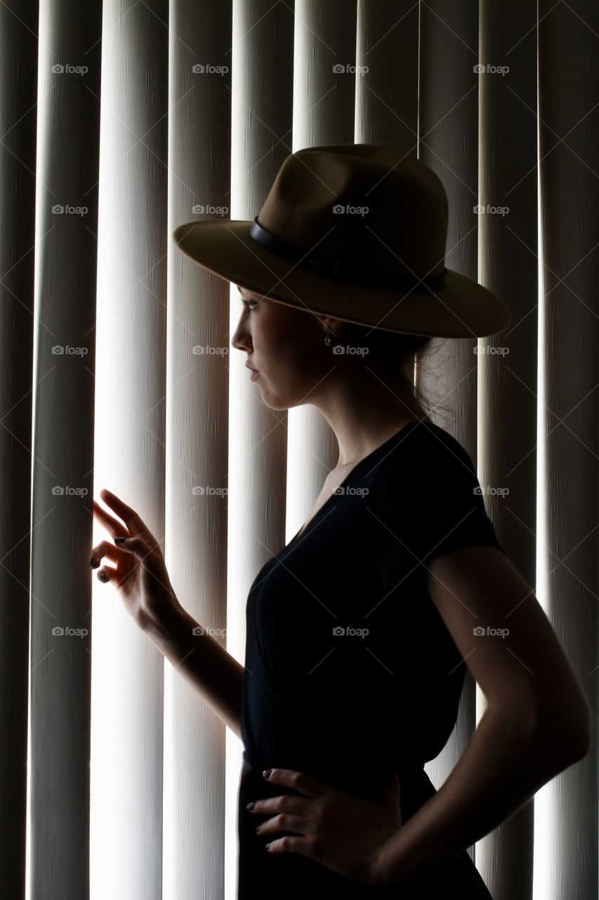 Woman looking through window blinds 