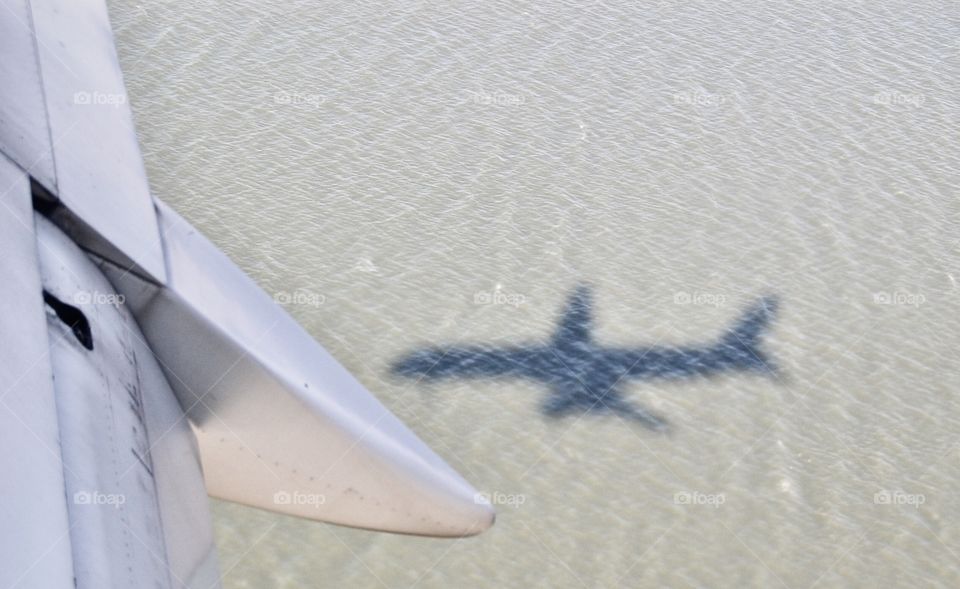 Jet’s shadow in the ocean approaching San Francisco Airport landing strip, perspective from plane’s window