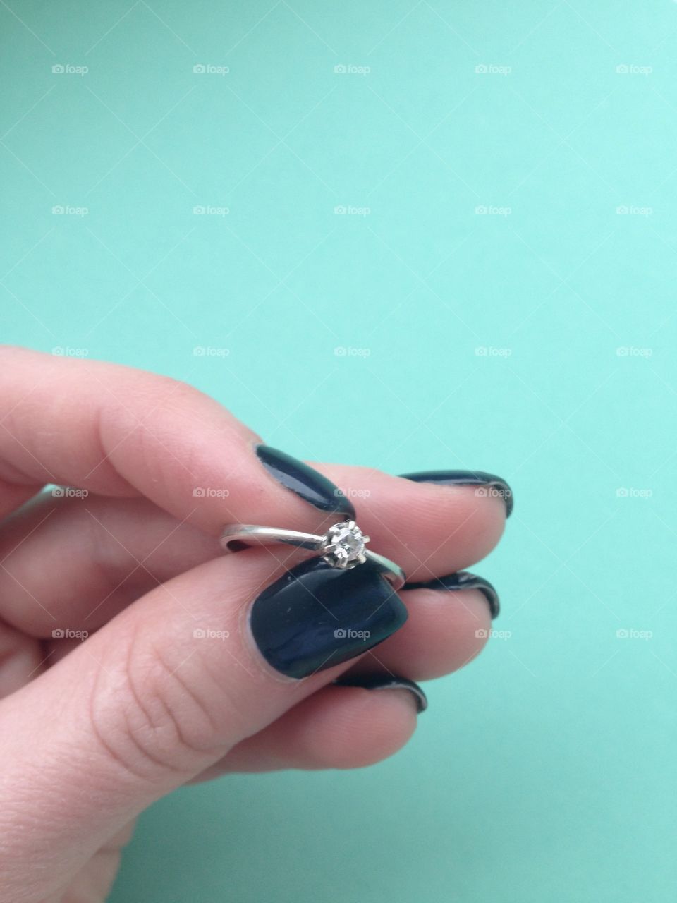 Hand holding  a ring with diamond on blue background 