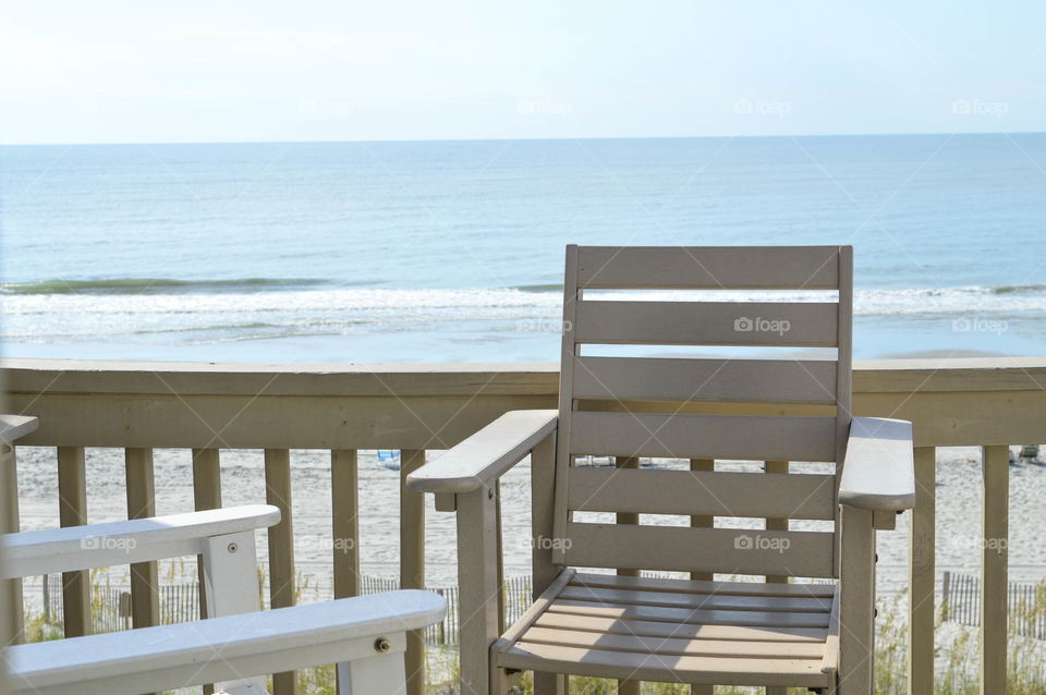 Empty chair on a balcony overlooking the beach