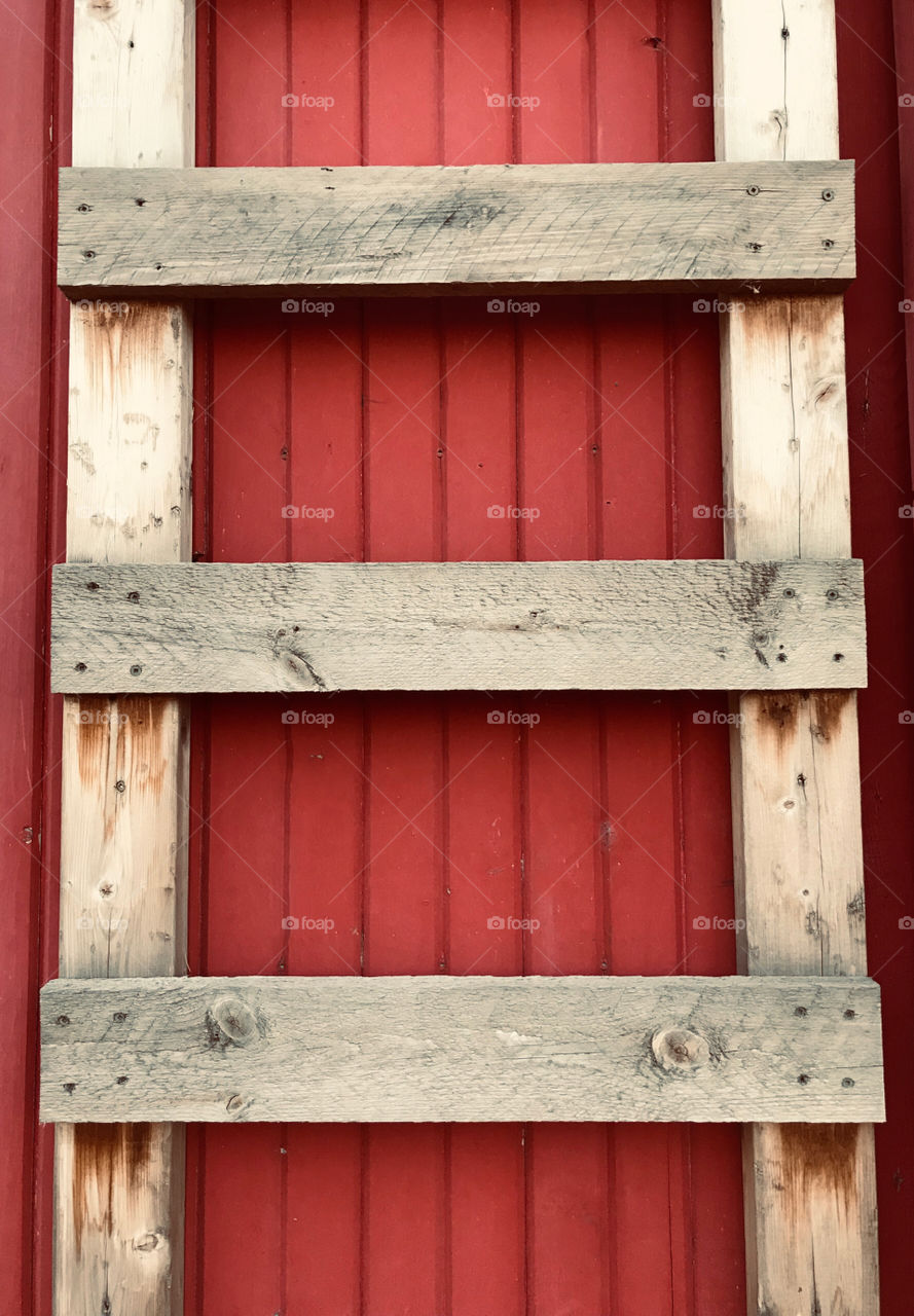Rustic ladder against a red wall