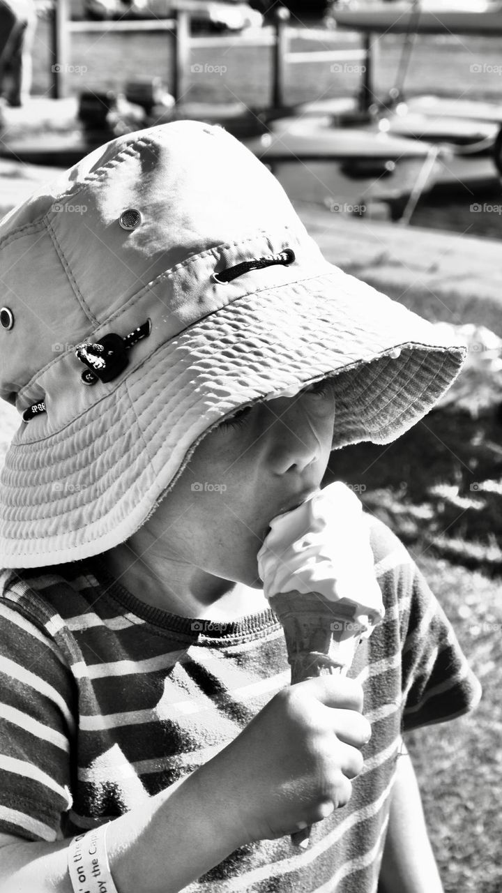 Kid with big hat licking his ice cream 