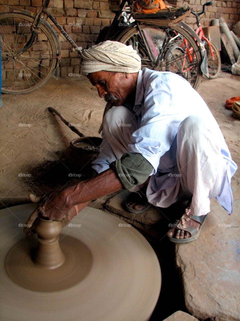 Man making a ceramic pot. Man using a wheel to create pottery in India