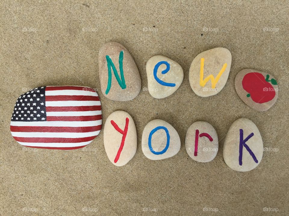 Souvenir of New York on stones. The big apple, New York city, souvenir on carved and painted stones on the sand