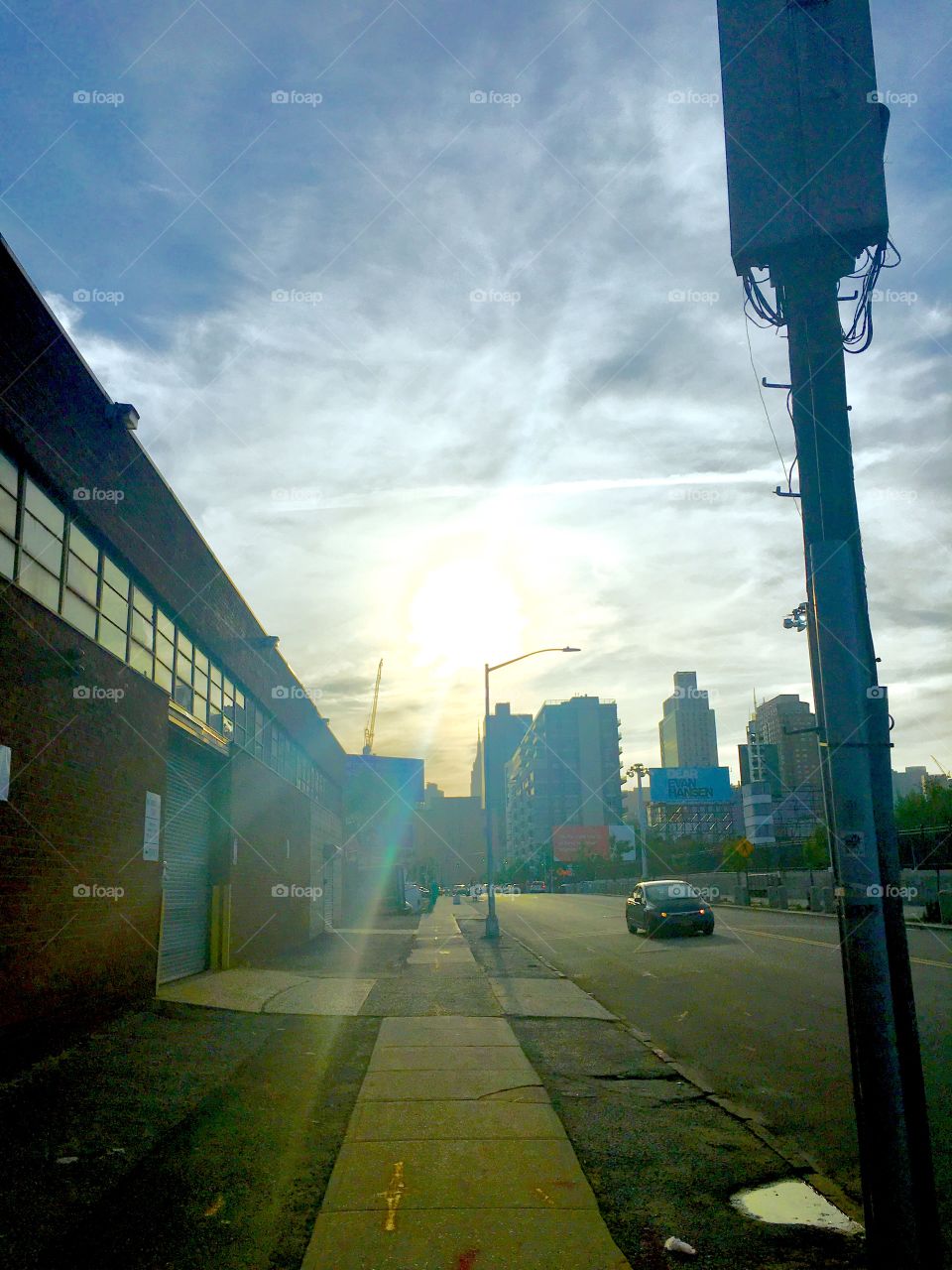 We’re at 1040 Borden Avenue, traffic light to the right looking towards the buildings in the distance. The evening sun is refracting against the clouds in the sky and causing lens flares. 2020. Hypnotic Productions