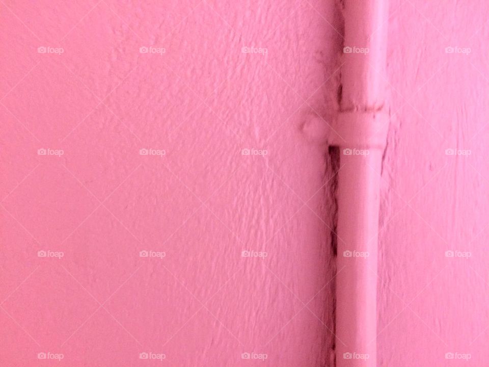 Pink colored painted wall with pipe