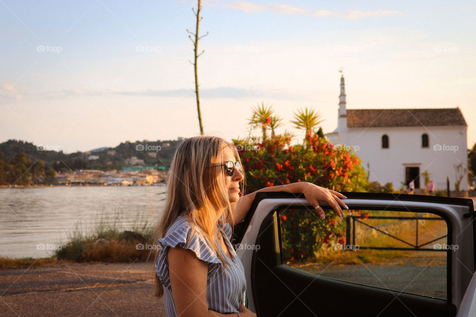 A woman leaning on car at sunset