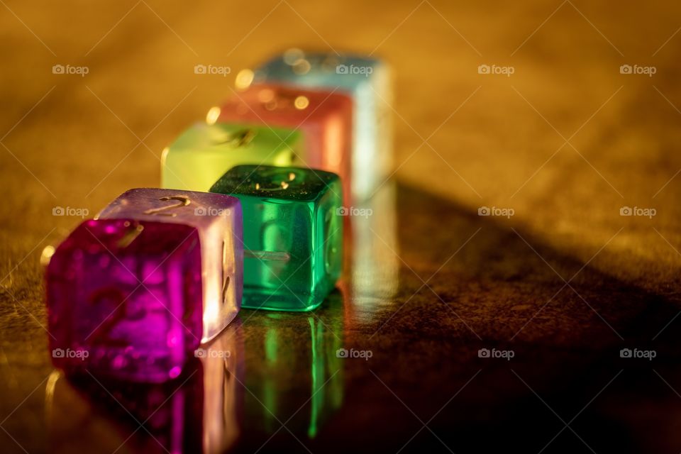 Translucent colorful dice on a shiny surface with beautiful reflections. 