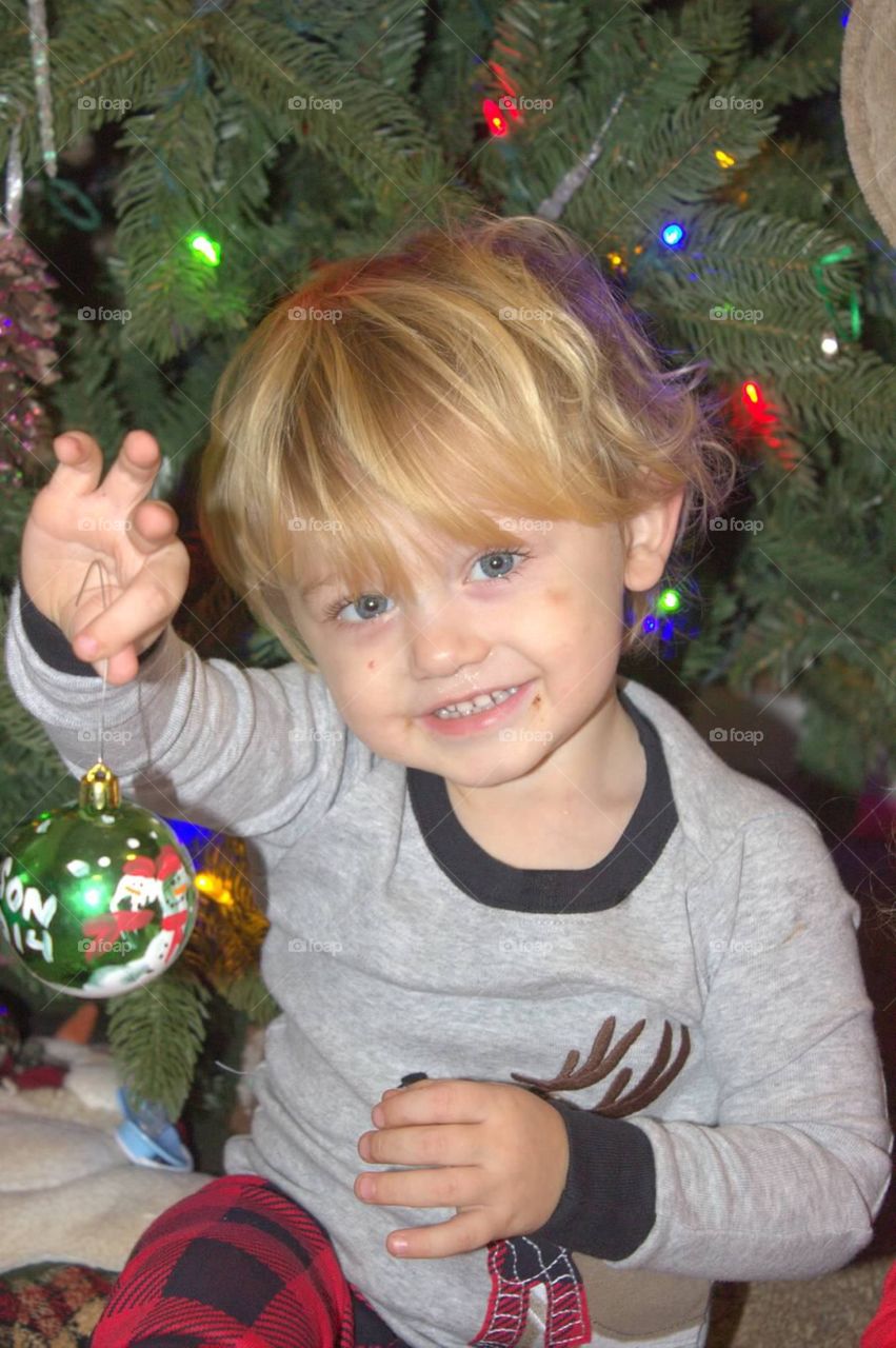 Sweet little boy holding up his Christmas ornament. 