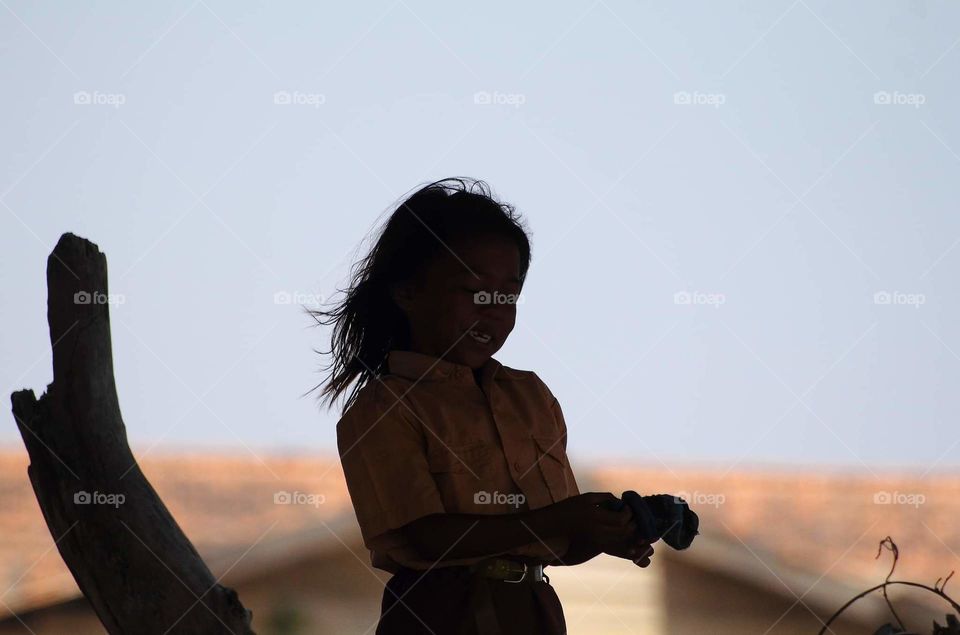 Second chance capturing . The little girl's hair is blown by the wind . Natural expression waited for seen anything interest of her . Not many attitude result. The girl and her friend used scout uniform after school. Not direct to reach their home .