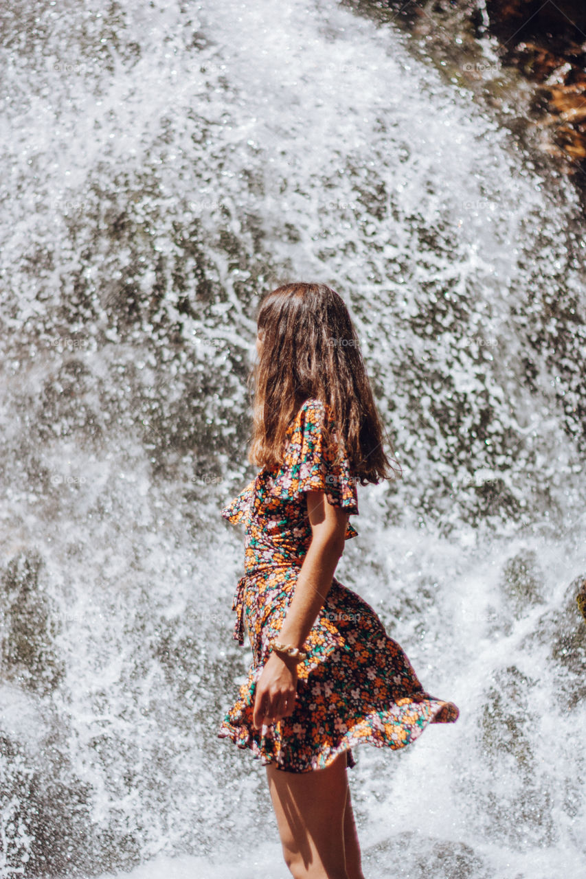 woman sitting next to a waterfall