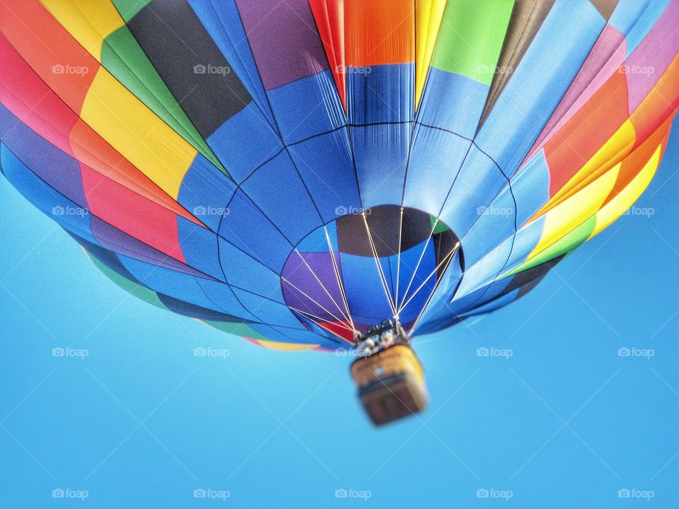 Captured a beautiful and colorful hot air balloon up high with the blue sky in the background.