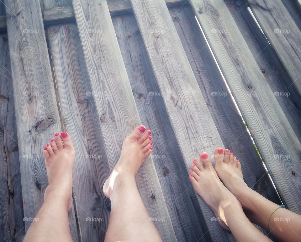 Feet up. Relaxing on the deck. Feet with red manicure.