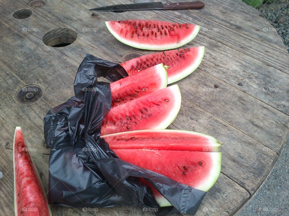 large pieces of watermelon chopped on a table with a knife