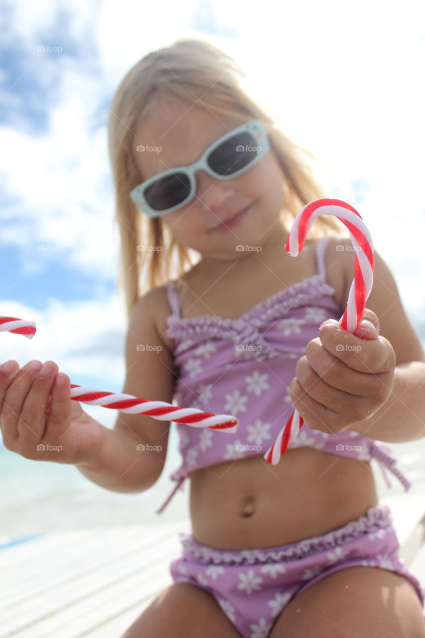 Child holding candy canes at the beach