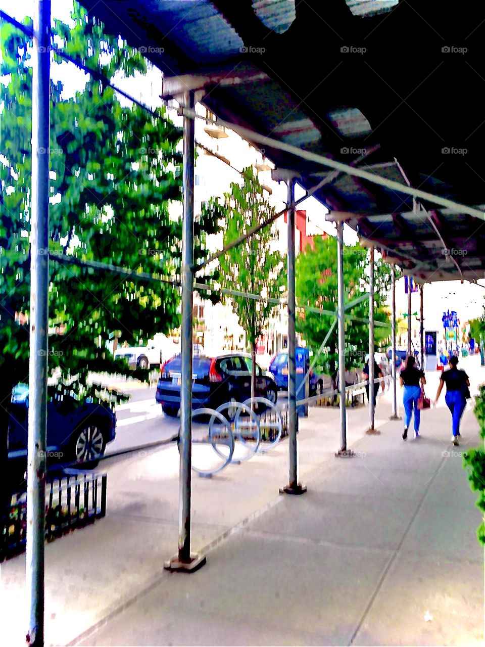 A Long Island City, Queens, NY underpass on the sidewalk with pedestrians, trees and parked cars also visible. 2019. Hypnotic Productions