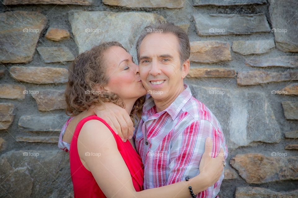 Mature wife kissing husband against stone wall
