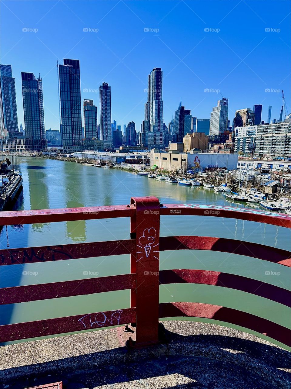 This is „Newtown Creek“ with all its boats seen from the „Pulaski Bridge“ that connects LIC, Queens to „Greenpoint“, Brooklyn. In the distance across the water of the „East River“ and behind LIC we can see „Manhattan“. 2024. Hypnotic Productions