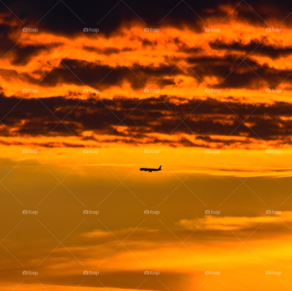 Aircraft on the sunset sky among the clouds