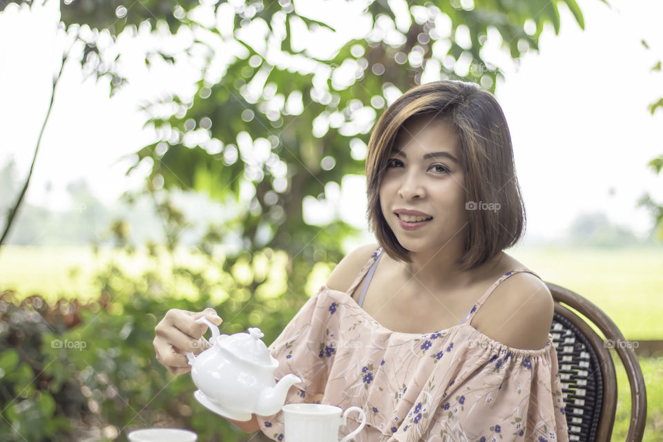 Kettles is made from ceramic tile in the hands of Asian women background blurry tree.