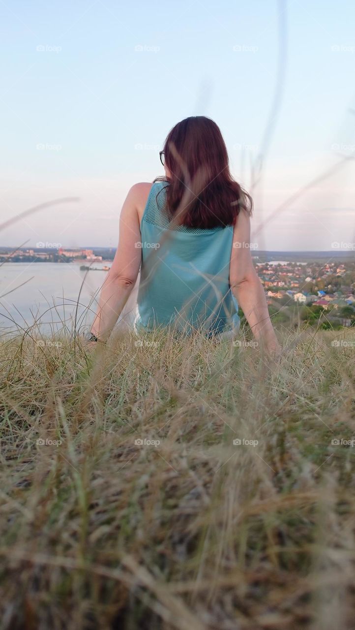 beautiful woman sits on the grass, summer, contemplation of nature, heat, evening, hair, girl in a top, grass, nature