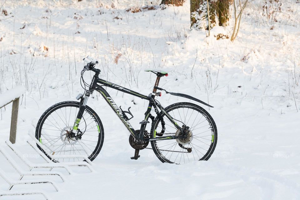 One lonely bicycle parked in snow at winter 