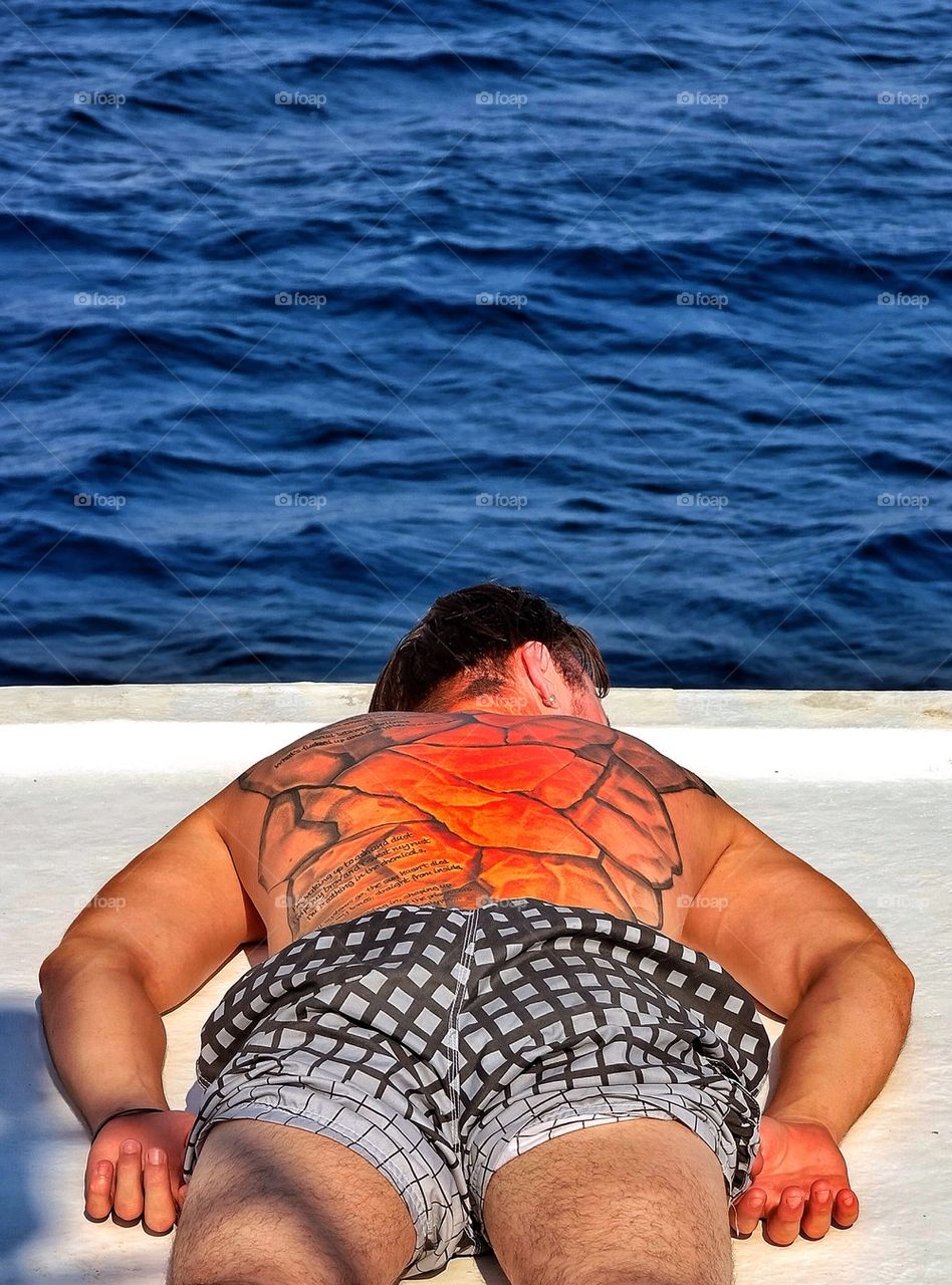 Tattoed man sunbathing on deck