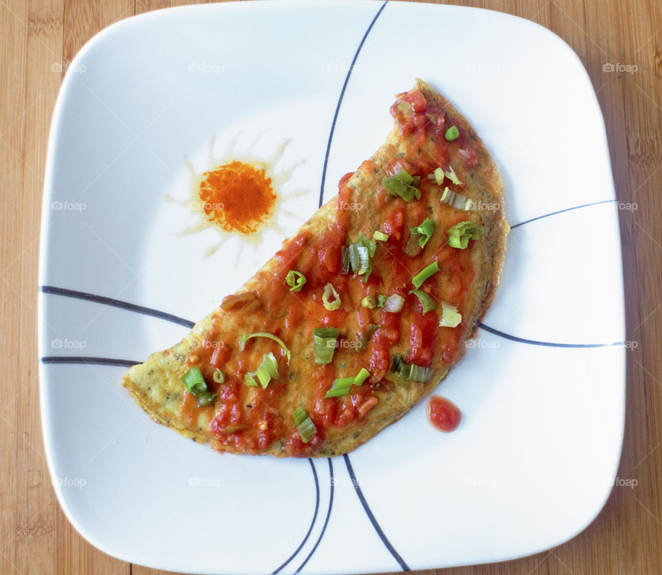 Overhead shot of an omelet topped with salsa and scallions.