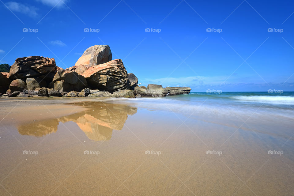Reflections of blue sky and rocks on the beach