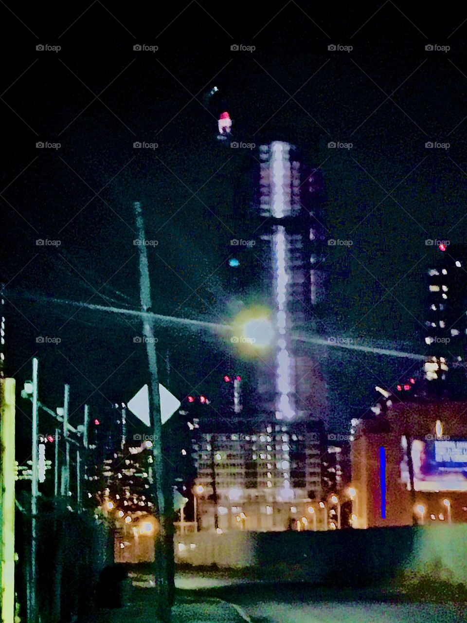 A view of the illuminated Long Island City in Queens, New York seen from the train tracks beneath the Pulaski Bridge with dramatic lens flare. Photo October 2020. Hypnotic Productions