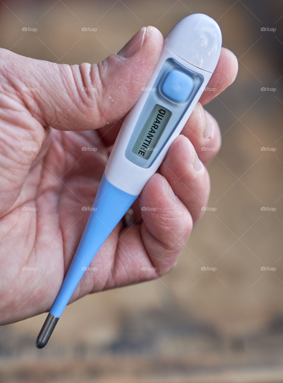 Male hand holds clinical thermometer with covid-19 text on the screen during global covid-19 or corona pandemic.