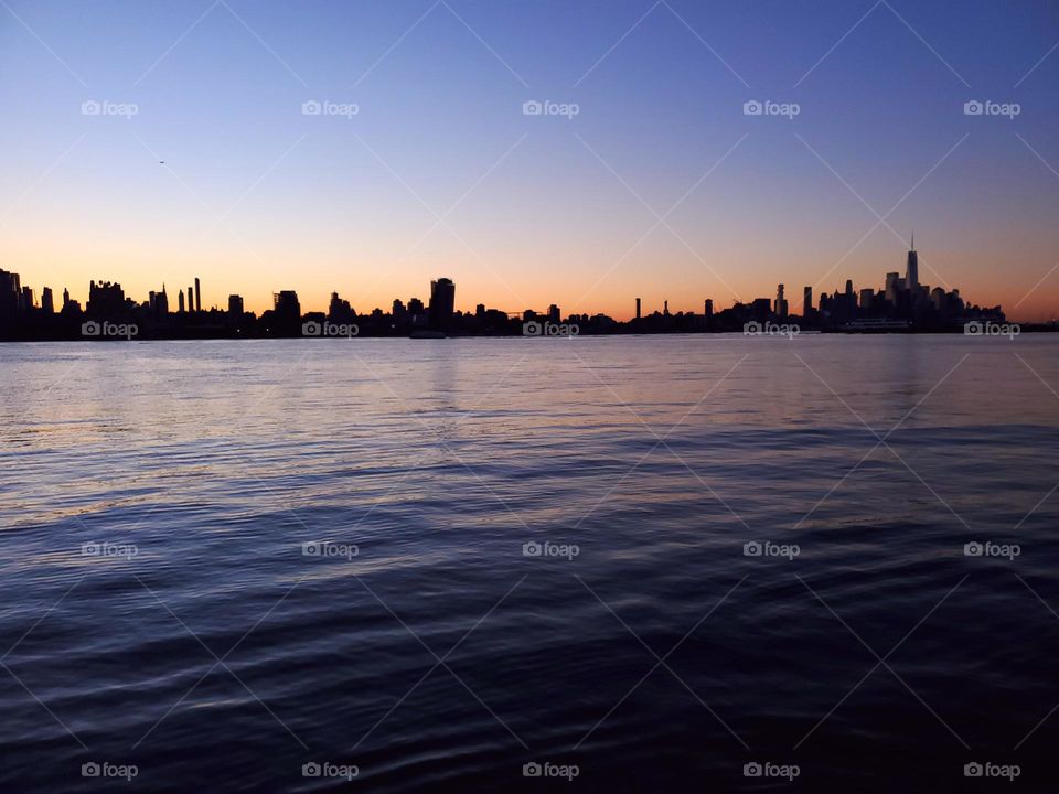 Looking across the Hudson River at the skyline of lower Manhattan on up to Midtown as the sun starts to rise