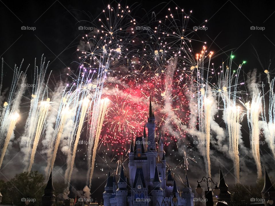 The finale of the fireworks show at magic Kingdom in Disney World. Many colorful fireworks going off behind Cinderella’s Castle 