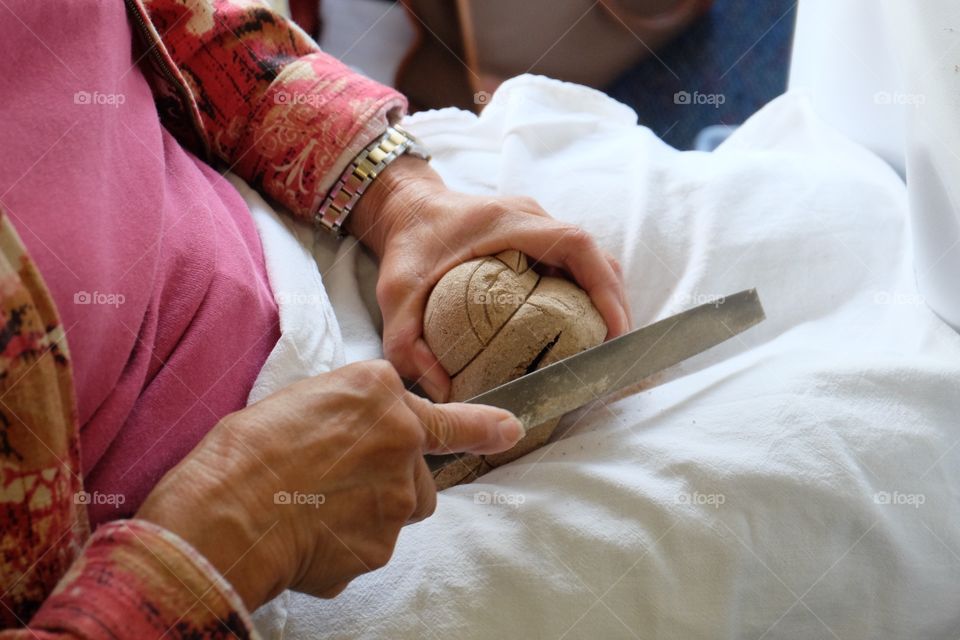 Shaving excess wood from a bird doll before covering fabric around it.