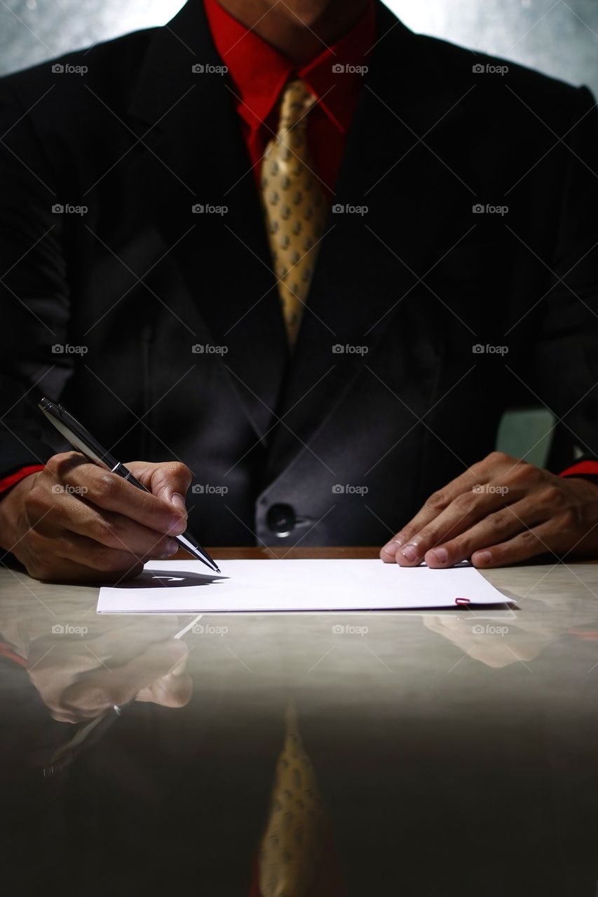 man in a suit writing on a paper