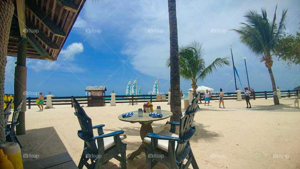Dining table on beach at popular vacation resort on tropical island. ocean in background.